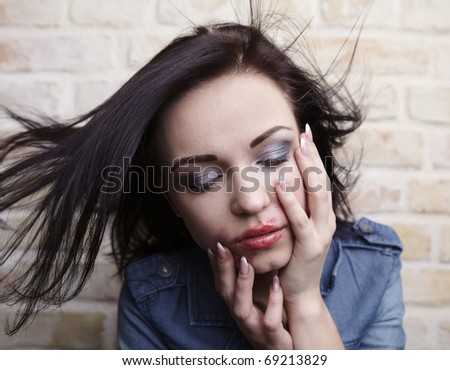 Depressed young brunette with smeared lipstick on her face.