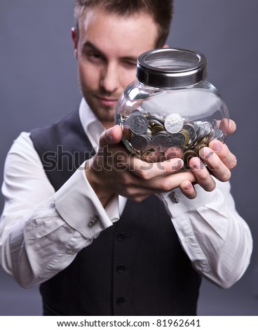 Young business man holding jar with coins  - retirement fund and savings concept
