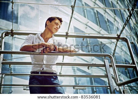 Young businessman standing in bright office balcony
