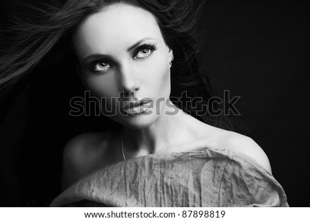 Beautiful sexy adult woman wearing dress over a black background. Black-white photo.