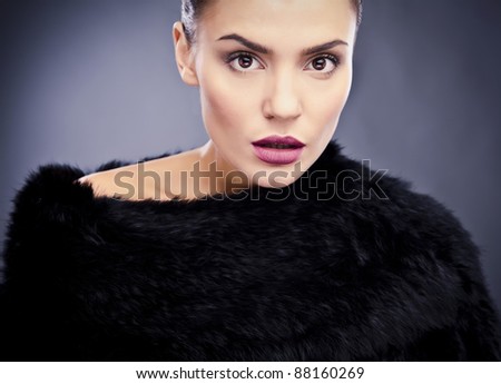 Close-up face portrait of stylish&fashionable pretty woman in fur against grey background.