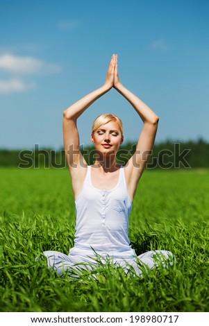 Beautiful young woman doing yoga exercise on field. Yoga concept.