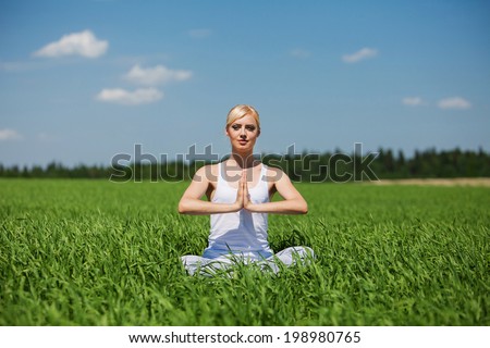 young woman doing yoga exercise on field. Yoga concept.
