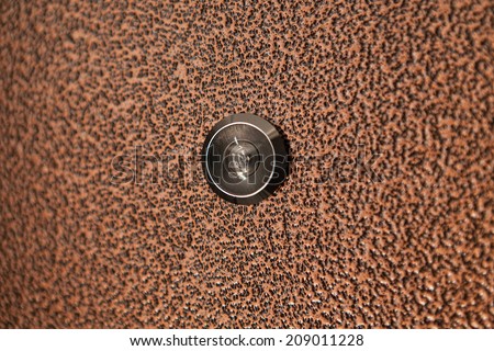 Black peephole in  brown iron door