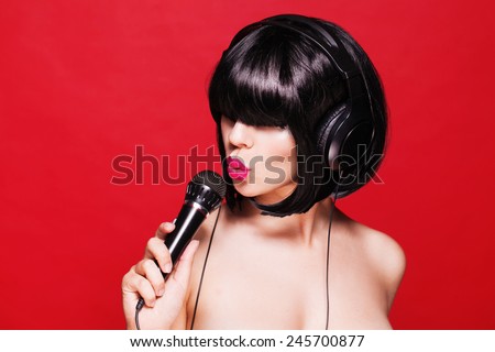 Woman listening to music on headphones enjoying a singing. Closeup portrait of beautiful girl with pink lips. Karaoke