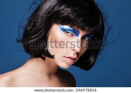 closeup beauty shot of young caucasian brunette model with blue eyeshadows and windy hair