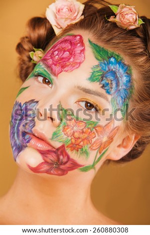 Close up beauty portrait of woman model with hand drawing flowers on her face. Color face art woman