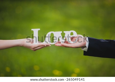 Bride and groom holding love word in natural environment
