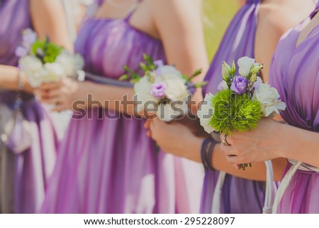 Row of bridesmaids in violet dresses with bouquets at wedding ceremony