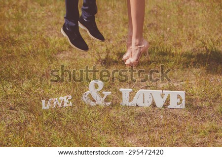 Feet of groom and bride and white love letters. Wedding details