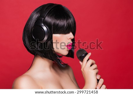 Stylish girl singing with a microphone, red background. Karaoke