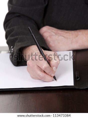 mature woman sitting behind desk and writing notes down
