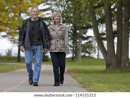 older casual couple walking in the park outdoors