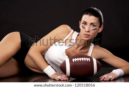 athletic brunette posing as american football girl on black background