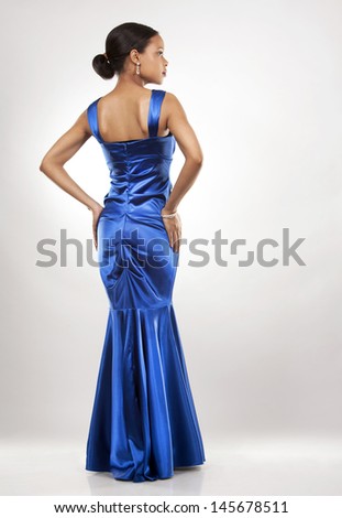 beautiful woman wearing blue evening dress on light background