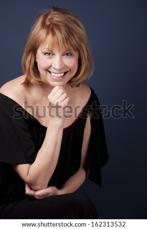 mature woman wearing black outfit on dark blue background