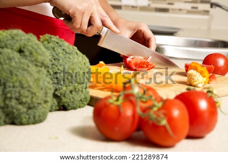 caucasian woman about to cut raw vegetables  on the kitchen
