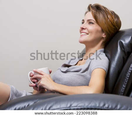 caucasian woman sitting in the living room drinking coffee