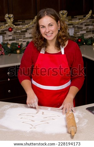 woman drawing into flour in the kitchen with Christmas ornaments