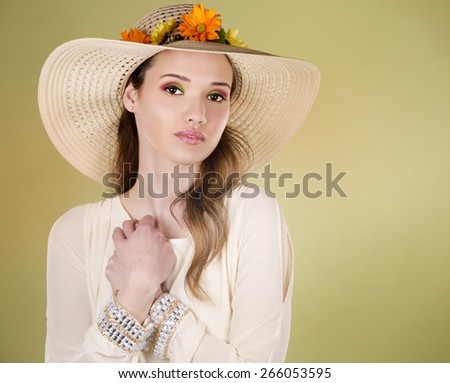 woman wearing hat with flowers on light green background