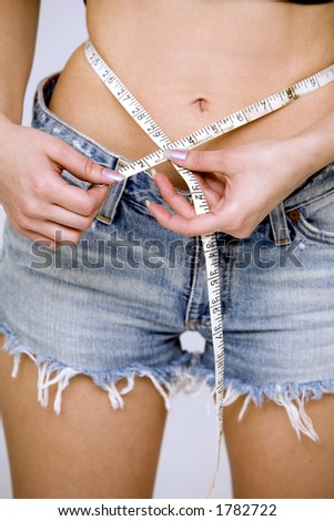 woman measuring her waist wearing jeans shorts