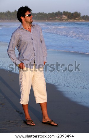 man wearing shirt and white pants on the beach during vacation