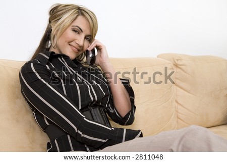 beautiful woman sitting on the sofa in living room wearing businesss wear and talking on the phone