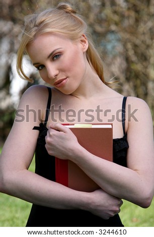 pretty blond woman reading book in a park