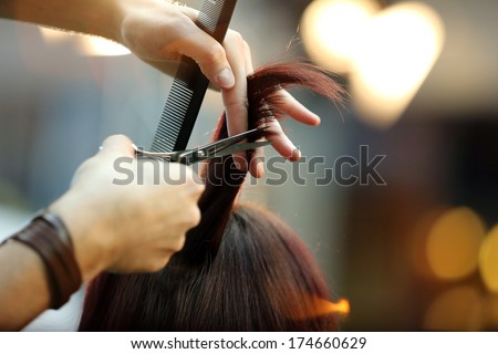 Hairdresser trimming blond hair with scissors
