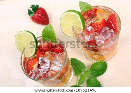 Colored drink with orange, strawberry, lime and ice