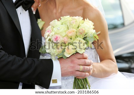 Newlyweds with wedding rose bouquet after wedding ceremony