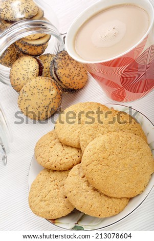 Sweet poppy seed shortbread biscuits with jam in a jar and cup of coffee