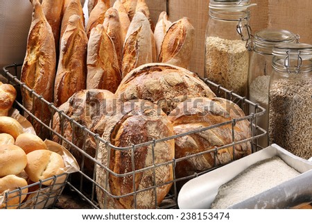 Fresh bread in metal basket in bakery on wooden background