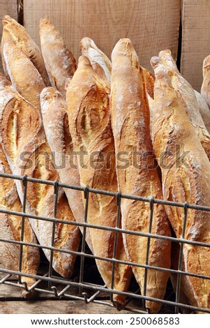 Fresh french baguette in metal basket in bakery on wooden background