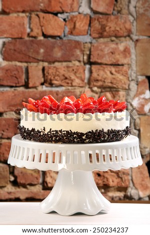Strawberry cream cake on brick wall background