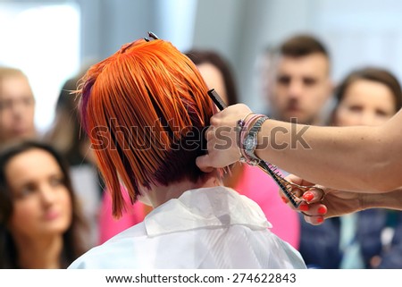 POZNAN - APRIL 18 : Hairdresser trimming red hair with scissors at The Look Beauty Vision Poznan 2015 on April 18, 2015 in Poznan, Poland