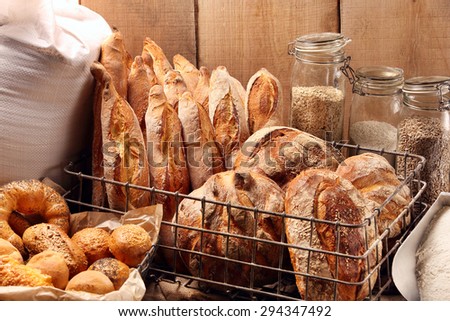 Fresh bread in metal basket in bakery on wooden background
