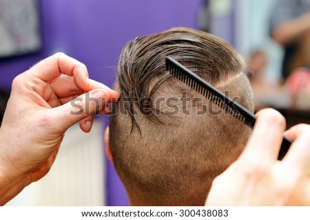 Barber modeling hair by comb at the hair salon