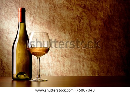 bottle with white wine and glass on a old stone. bottle in the foreground