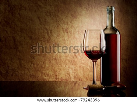 white bottle with red wine and glass and cork with a corkscrew on a old stone
