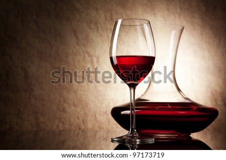 decanter with red wine and glass on a old stone background
