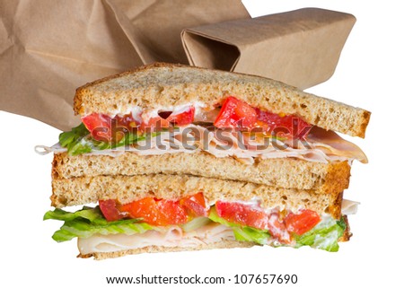 Hearty brown bag lunch sandwich of turkey with lettuce, tomato and mayo.