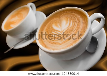Two cups of gourmet coffee house cappuccino against a silky background