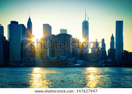 Unique View Of East River And New York City Skyline With Sun Reflecting Off Buildings Of Lower Manhattan At Sunset.