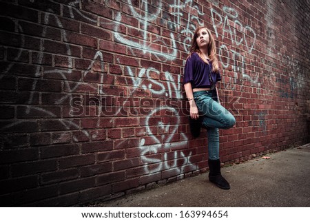 Cute teenage girl against urban graffiti covered wall