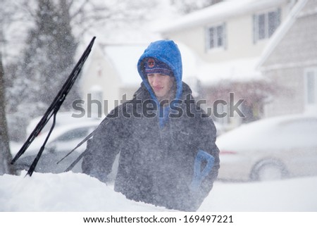 WEST HEMPSTEAD,  NY - JAN 3:  Teenager clears snow from his car on Long Island, NY on Jan 3 2014 after snow storm. This powerful nor\'easter named Hercules caused blizzard conditions on Long Island.