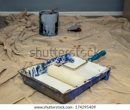 Realistic image of paint pan and roller on drop cloth during interior painting project
