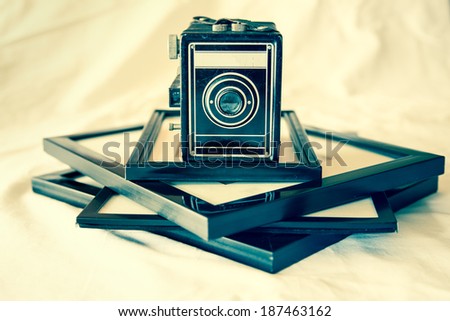 Retro toned vintage box camera and framed photographs