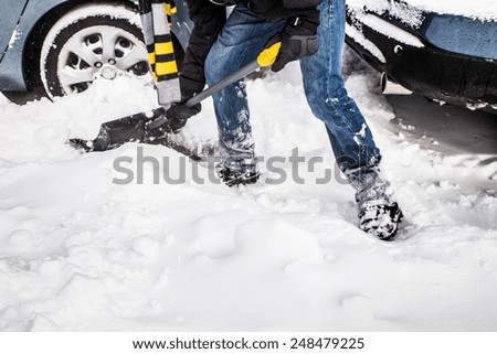 Snow removal with shovel and car in background