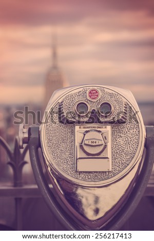 Retro style toned image of coin operated binoculars viewing New York City and Empire State Building
